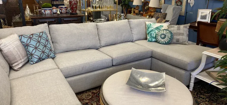 A sectional couch is sitting next to a round coffee table in a living room.