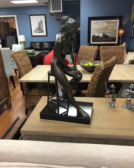 A statue of a woman sitting on a chair in a living room