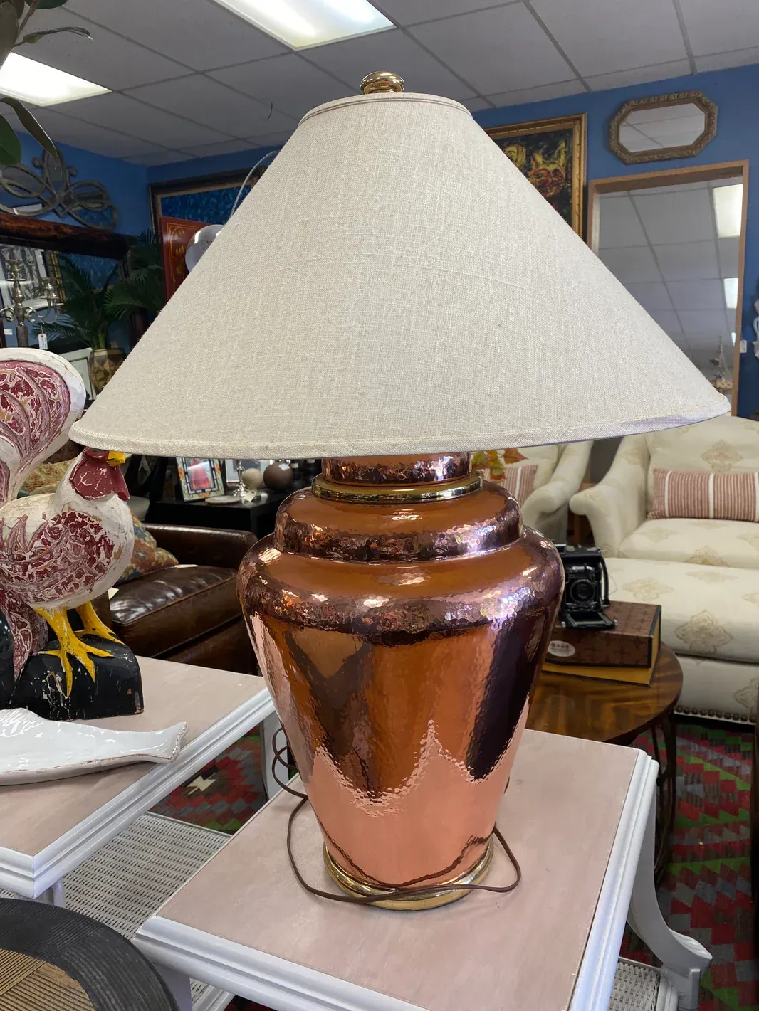 A lamp with a white shade is sitting on a table in a living room.