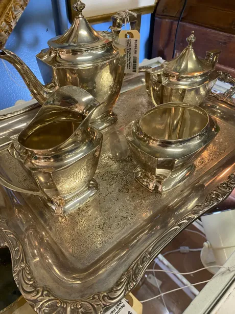 A silver tea set is sitting on top of a silver tray.