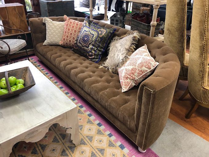 A brown couch with pillows on it is sitting next to a white coffee table.