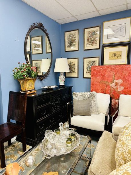 A living room with a couch , chair , dresser and mirror