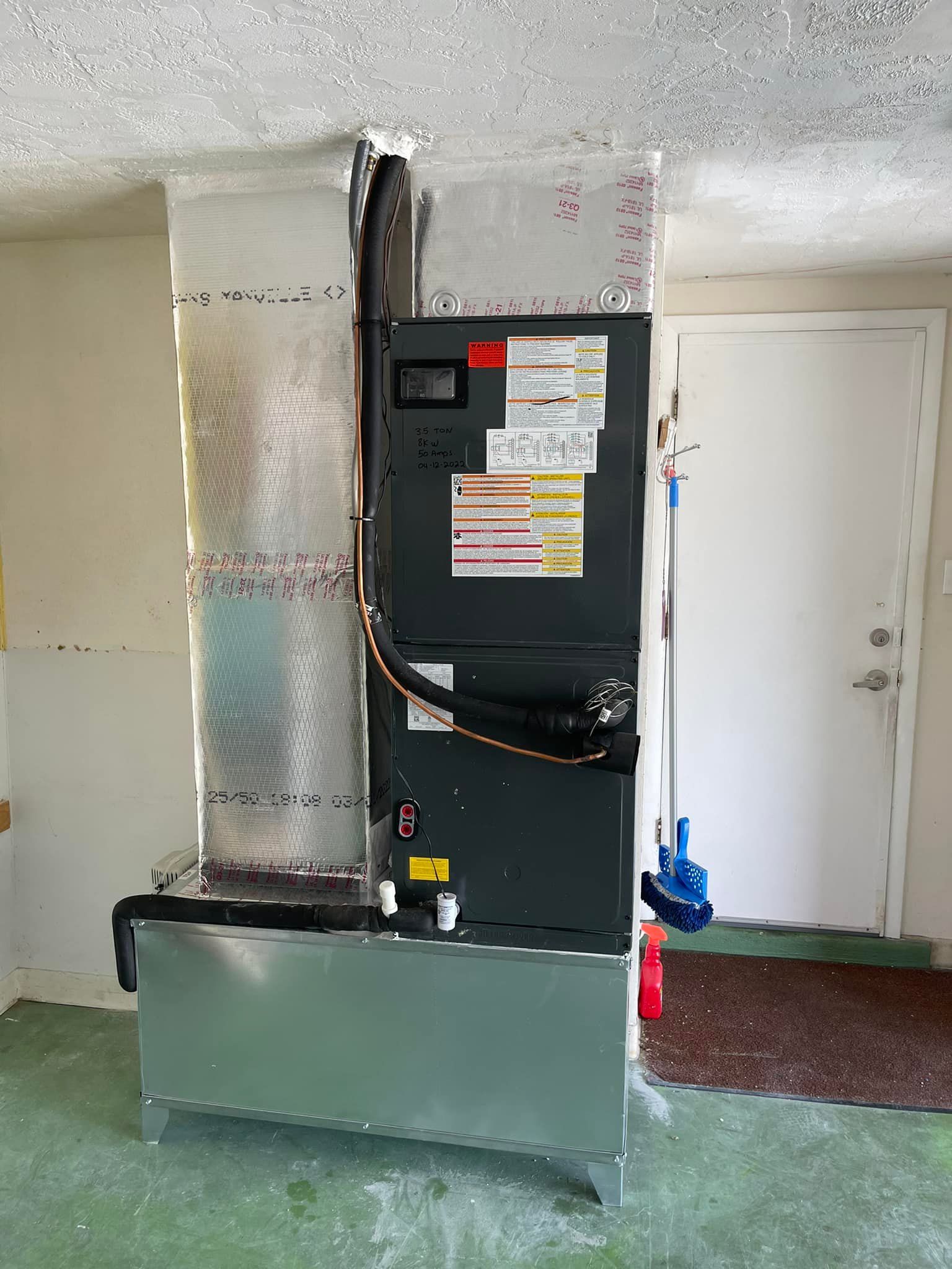 A large air conditioner is sitting in a room next to a door.