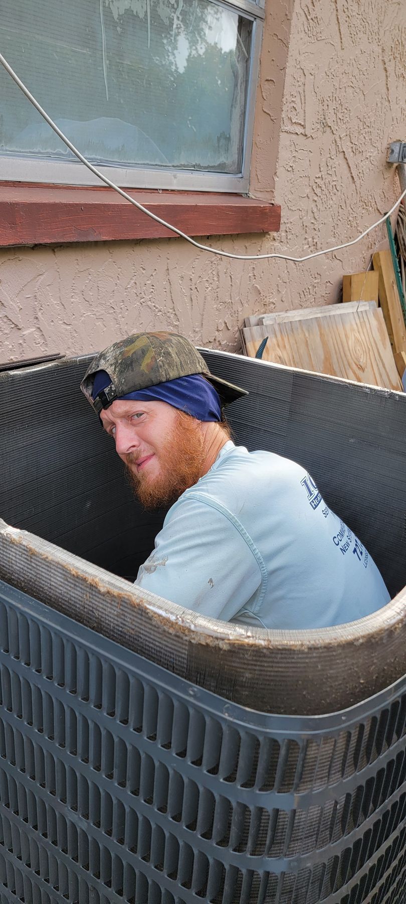 A man is sitting inside of an air conditioner.
