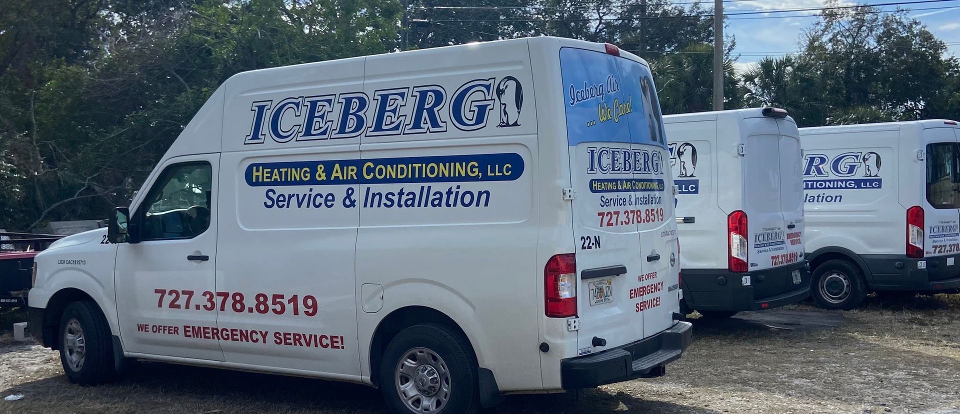 Three white vans are parked next to each other in a parking lot.