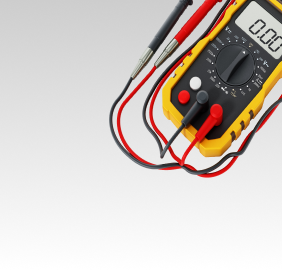 Yellow multimeter with red and black probes on a gradient gray background, displaying 0.00 | Libertyville Kar Care