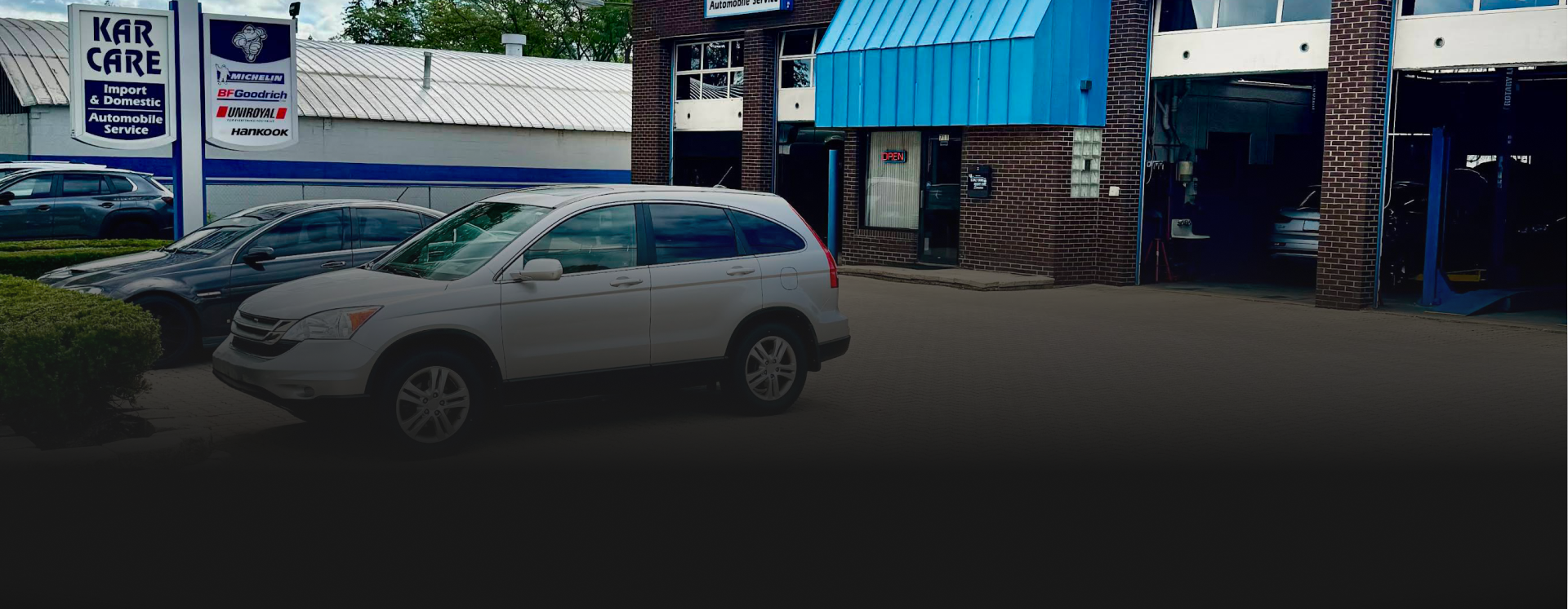 Mechanic working on a car in a garage. Blue cabinet and tools in the foreground | Libertyville Kar Care