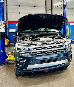Black Ford Expedition SUV with hood open in a mechanic shop | Libertyville Kar Care