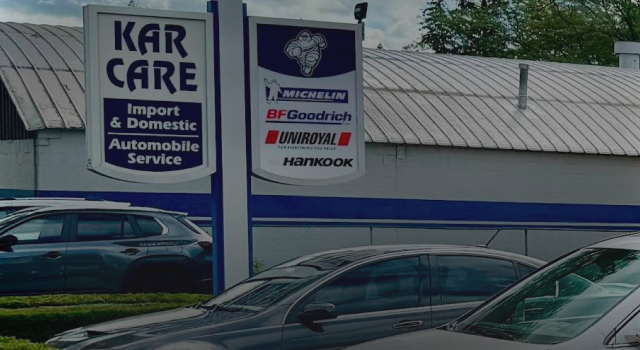 Mechanic working on a car in a garage with the hood open, blue cabinet in front | Libertyville Kar Care