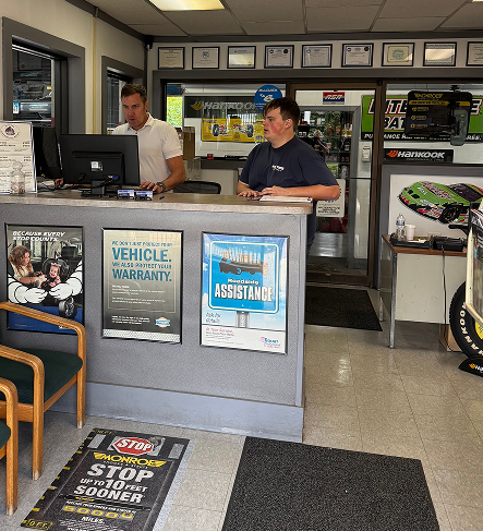 Two men behind a counter in an auto repair shop. One works on a computer, the other takes notes | Libertyville Kar Care