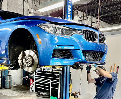 Blue car on a lift in a garage, being worked on by a person | Libertyville Kar Care