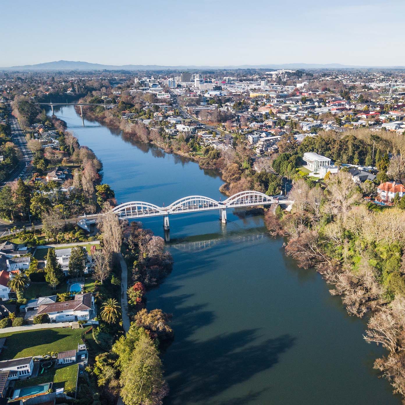 An aerial view of a bridge over a river with a city in the background.