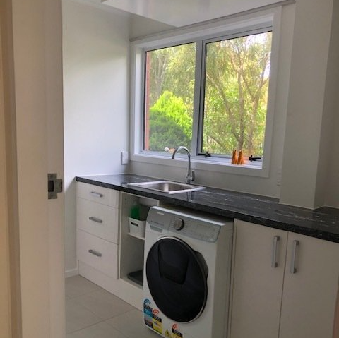 A laundry room with a washer and dryer , sink , and window.