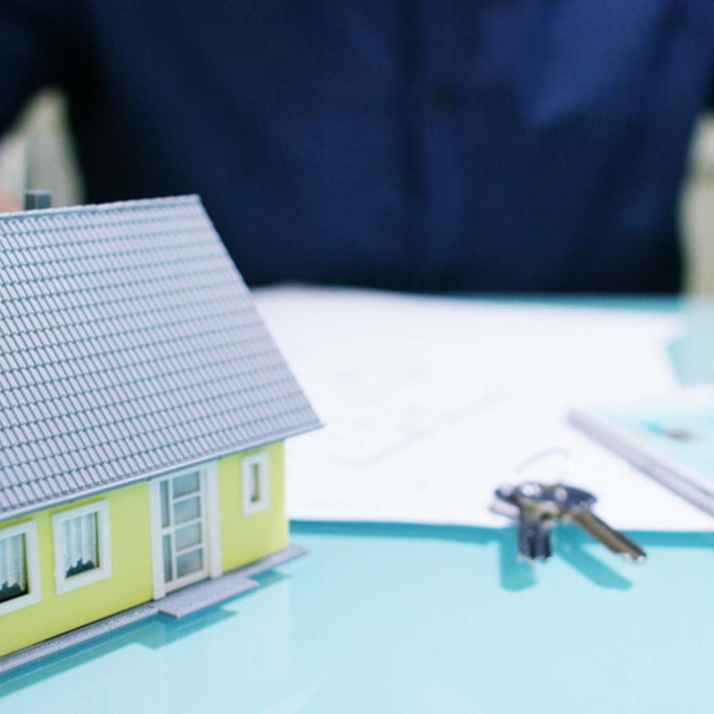 A model house is sitting on a table next to keys.