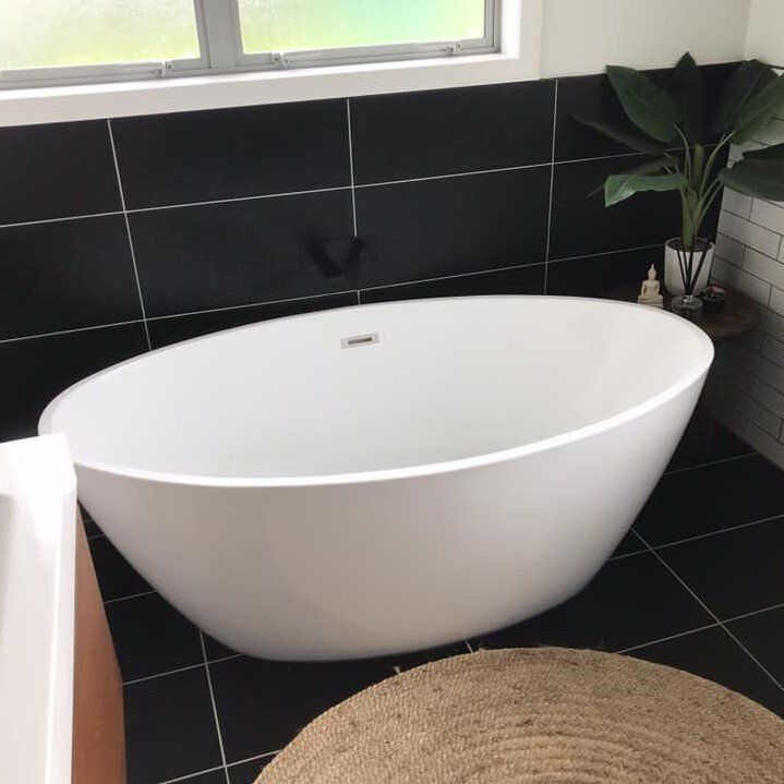 A white bathtub is sitting in a bathroom next to a window.