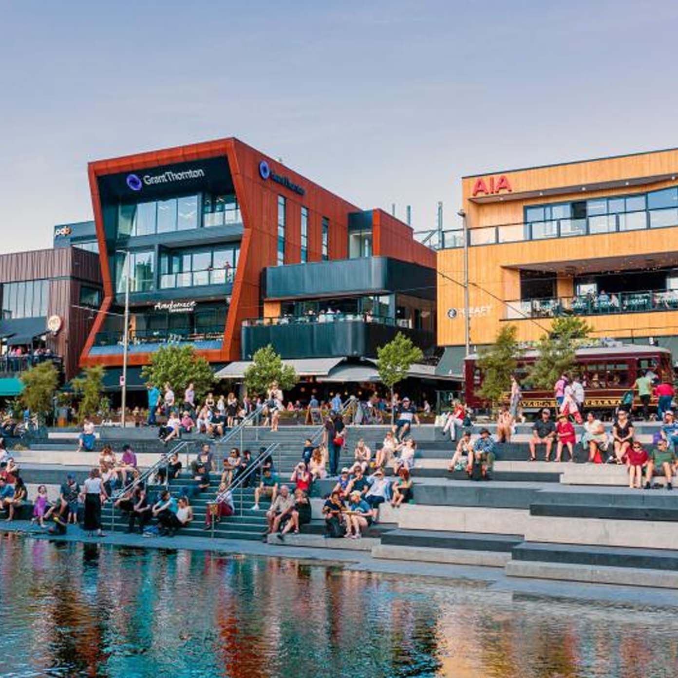 A group of people are sitting on steps next to a body of water.