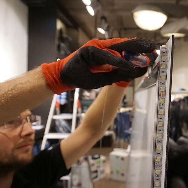 A man wearing gloves is working on a light strip