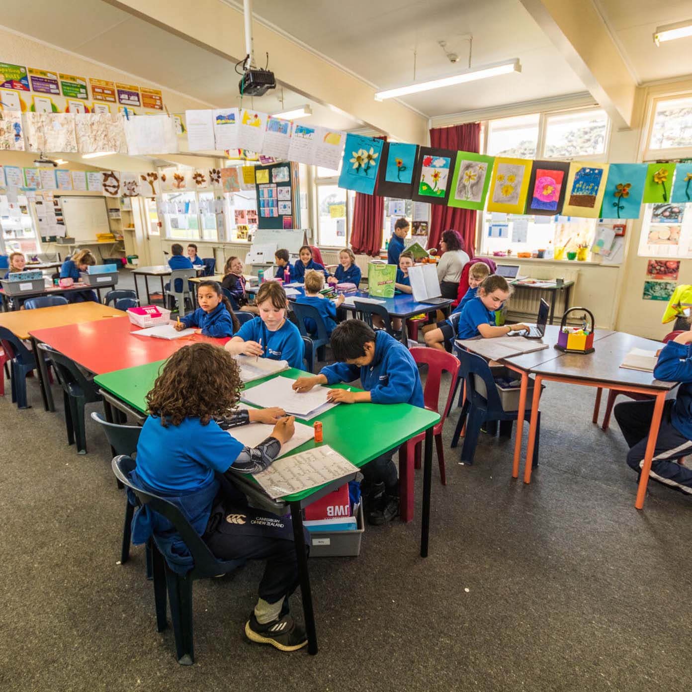 A group of children are sitting at tables in a classroom.