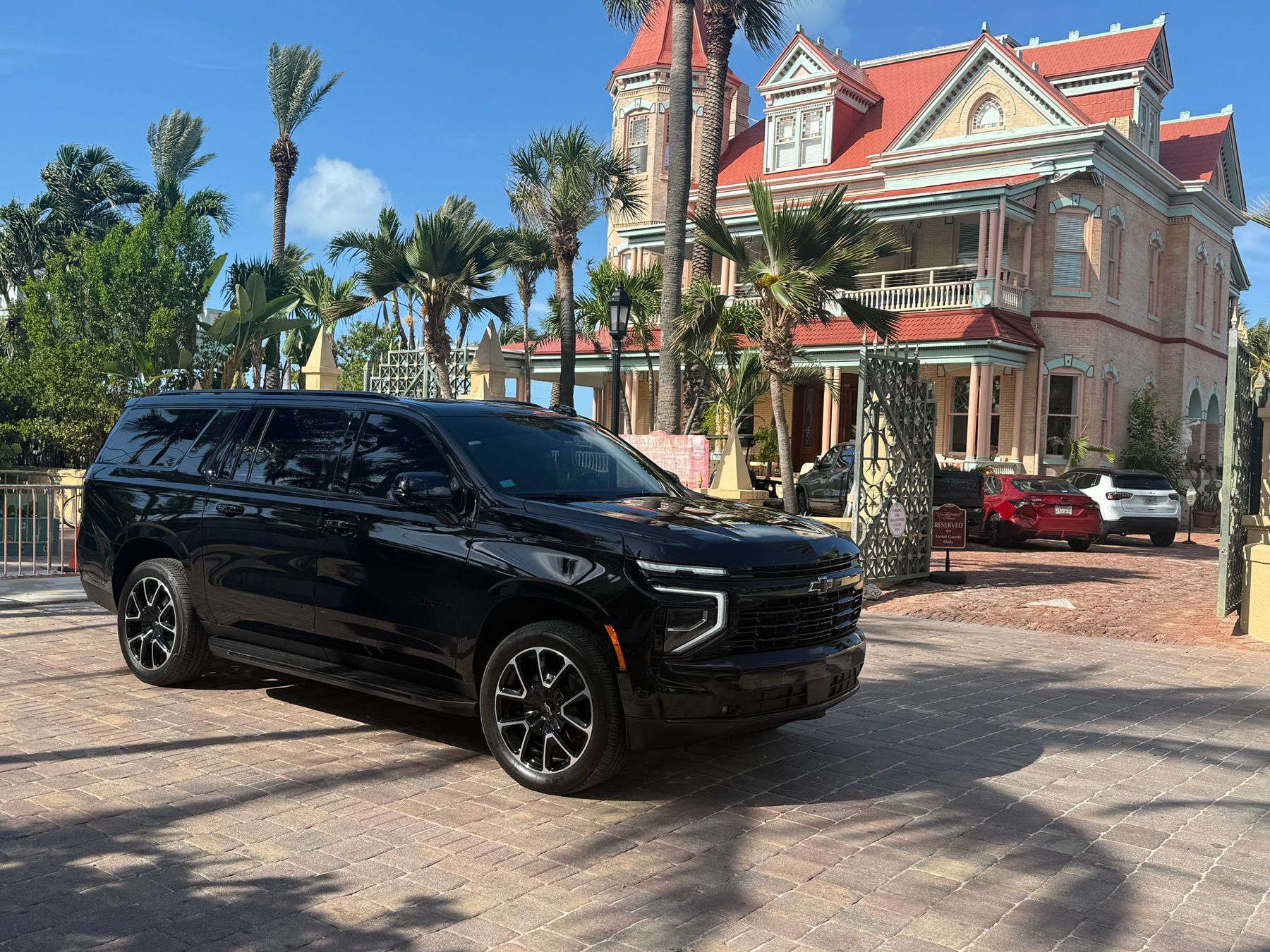 Black SUV parked in front of a large, ornate historic house with palm trees in Key West, Florida.