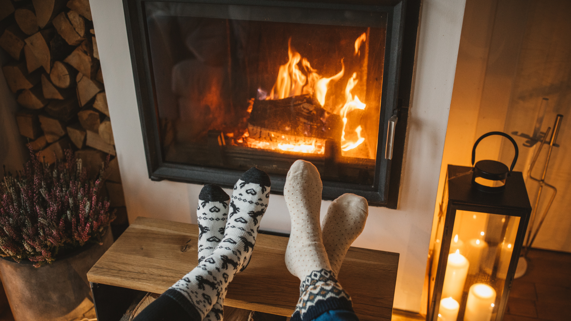 A person is sitting in front of a fireplace with their feet up.