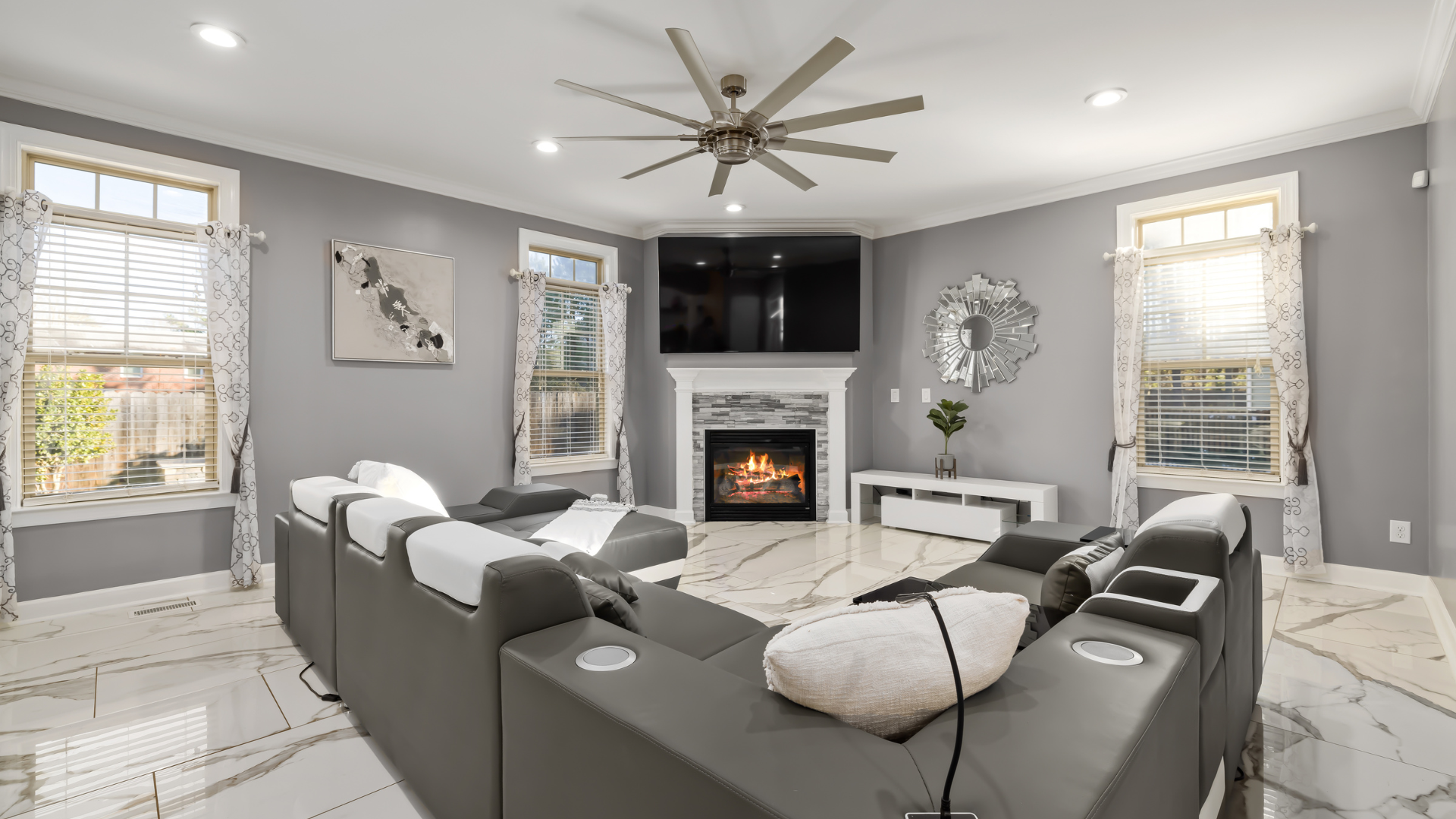 A living room with a couch , fireplace , television and ceiling fan.