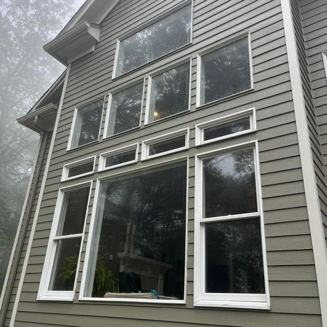 Gray house with multiple white-framed windows on a foggy day.