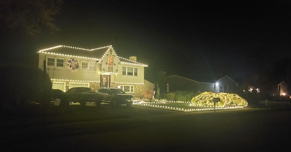 A two-story house covered in white Christmas lights at night.