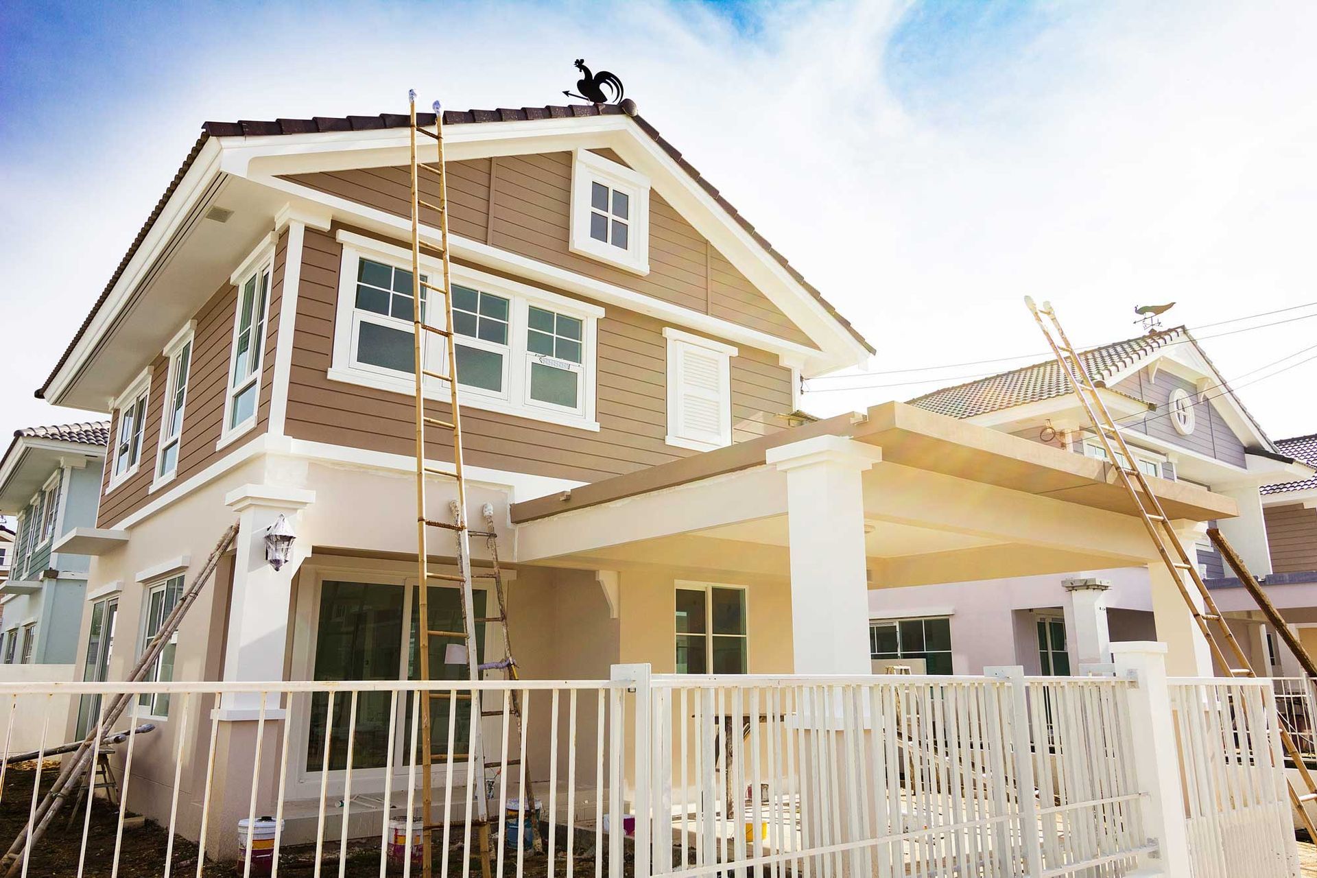 Newly constructed house with tan siding, white trim, and a ladder leaning against it. Newly constructed house with tan siding, white trim, and a ladder leaning against it.