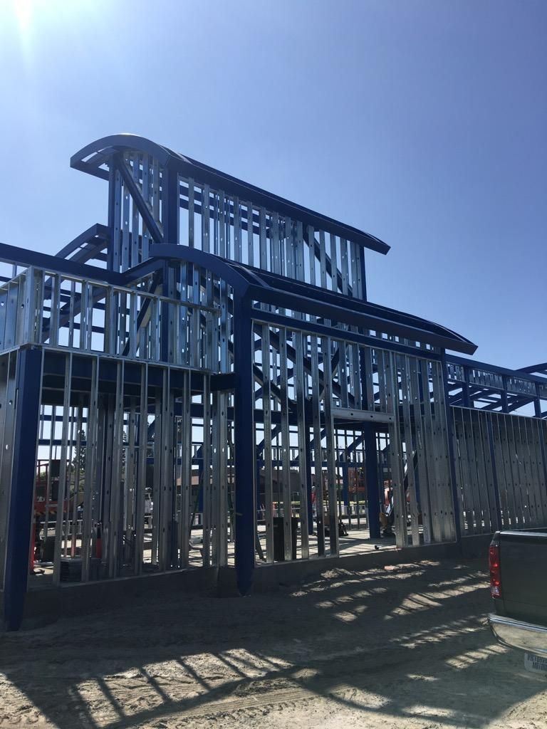 Steel-framed building under construction with exposed beams against a bright blue sky