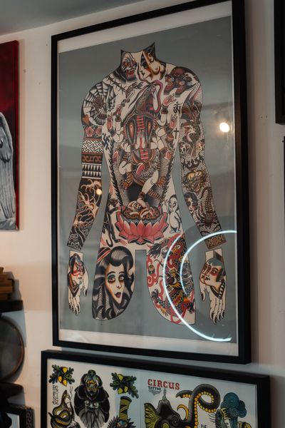 Framed abstract collage artwork with a patterned human figure and faces displayed on a wall.