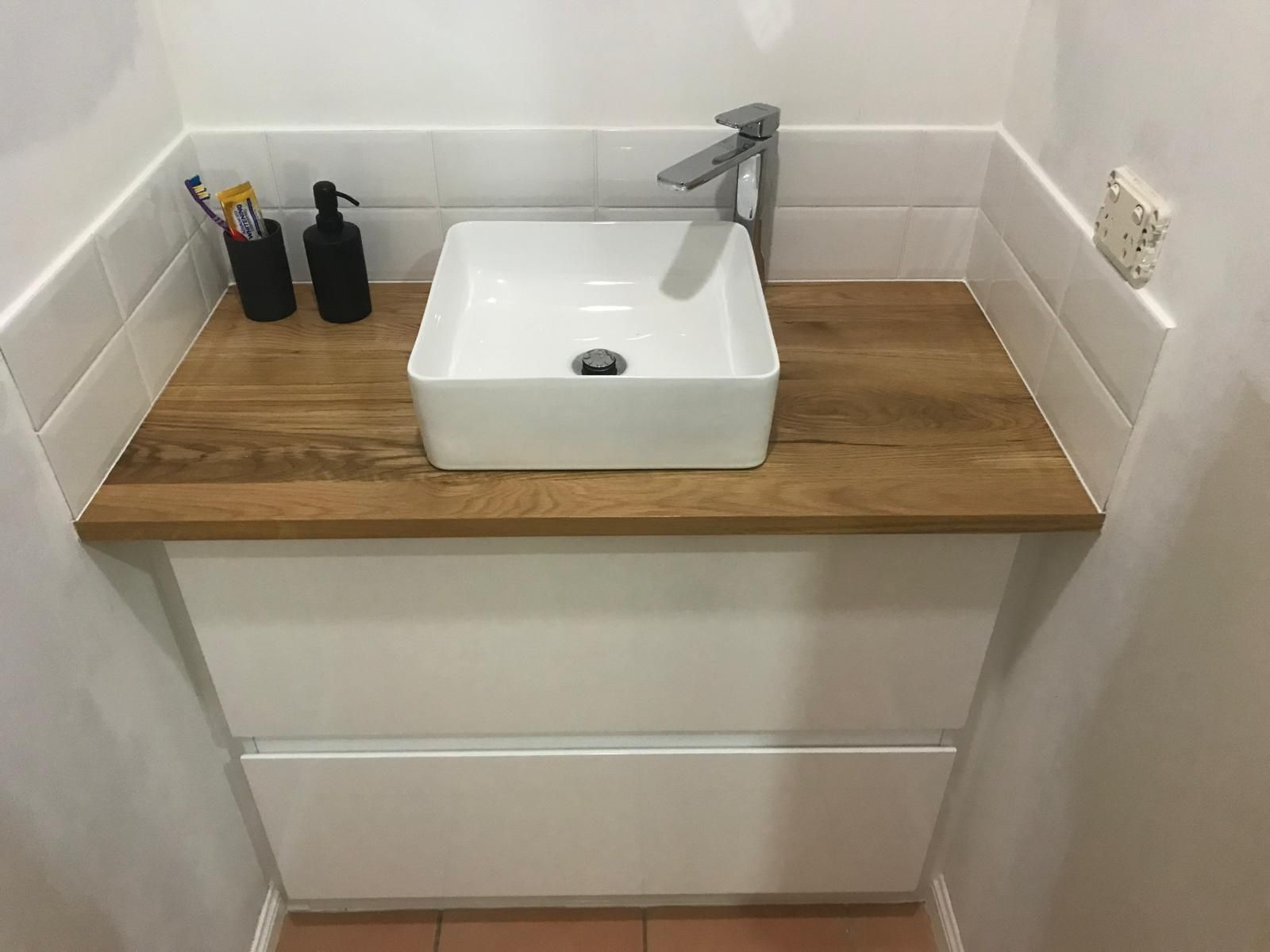 A Person is Installing Tiles on a Wall — Slim Fox Home Improvements in Mooroobool, QLD