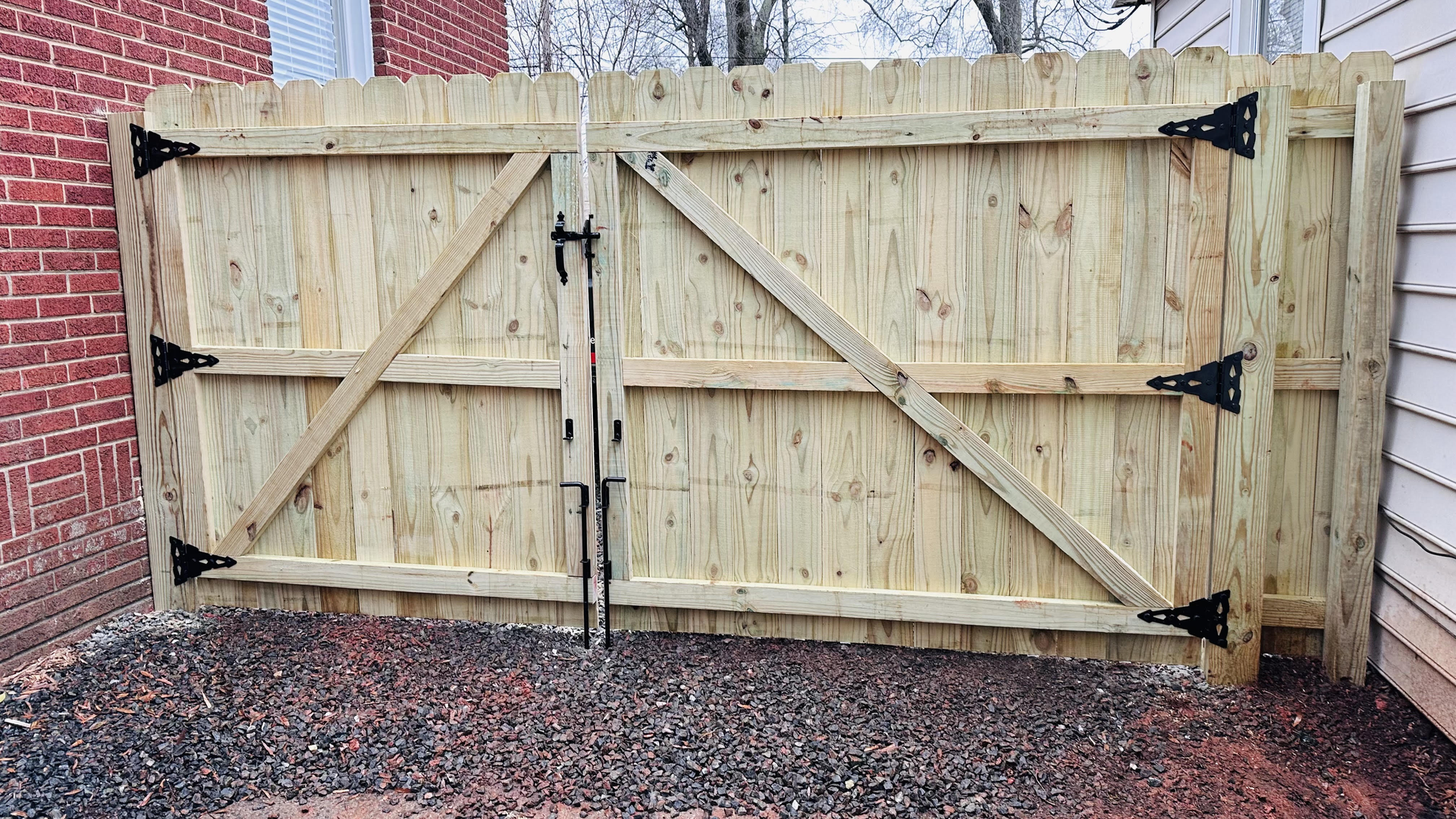 A wooden fence with a gate is sitting next to a brick building.