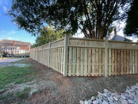 A black fence surrounds a driveway in a backyard.