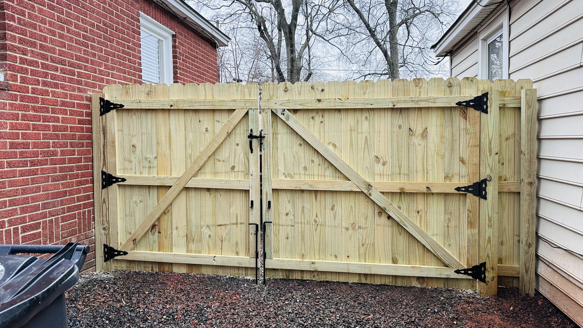 A wooden fence is sitting in front of a brick house.