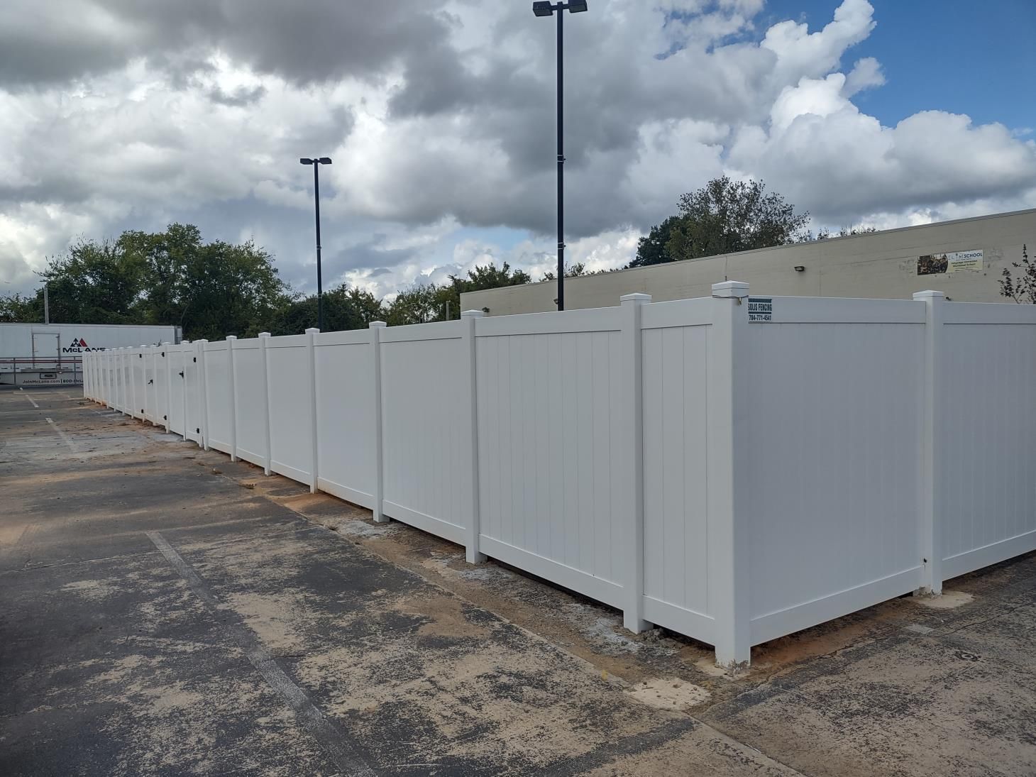 A row of white fences are lined up in a parking lot.