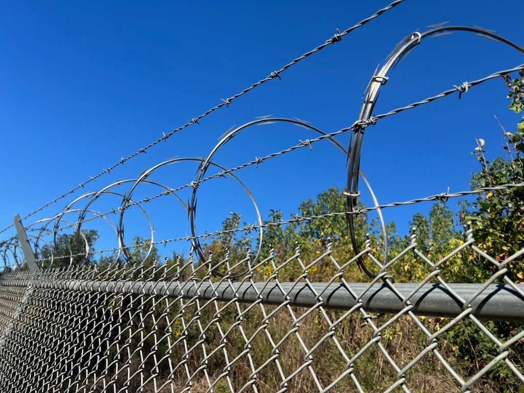 A chain link fence is surrounding a dirt area.