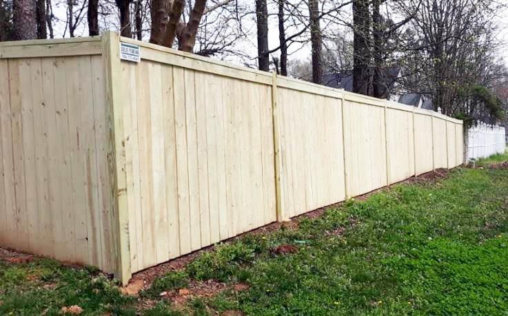 A wooden fence with a gate in front of a house.