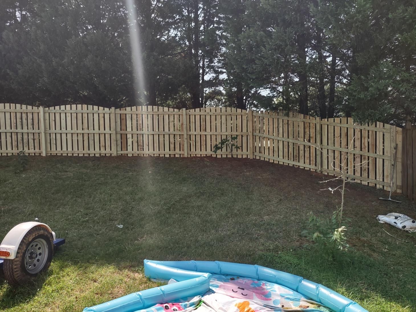 A wooden fence with a gate in the middle of a field.