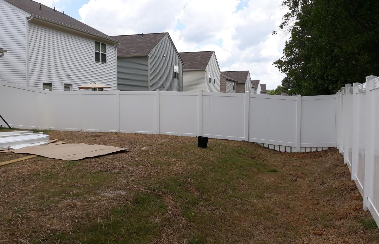 A black wrought iron gate surrounds a driveway in front of a house.