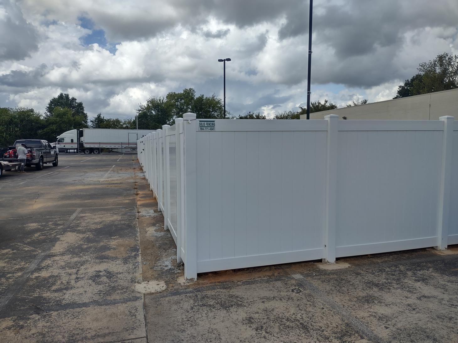 A black fence surrounds a driveway in a backyard.