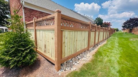 A wooden fence surrounds a large yard in front of a house.