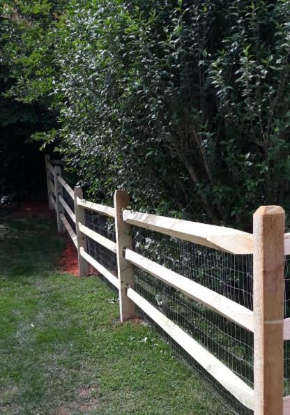 A wooden fence with a gate in the middle of a field.