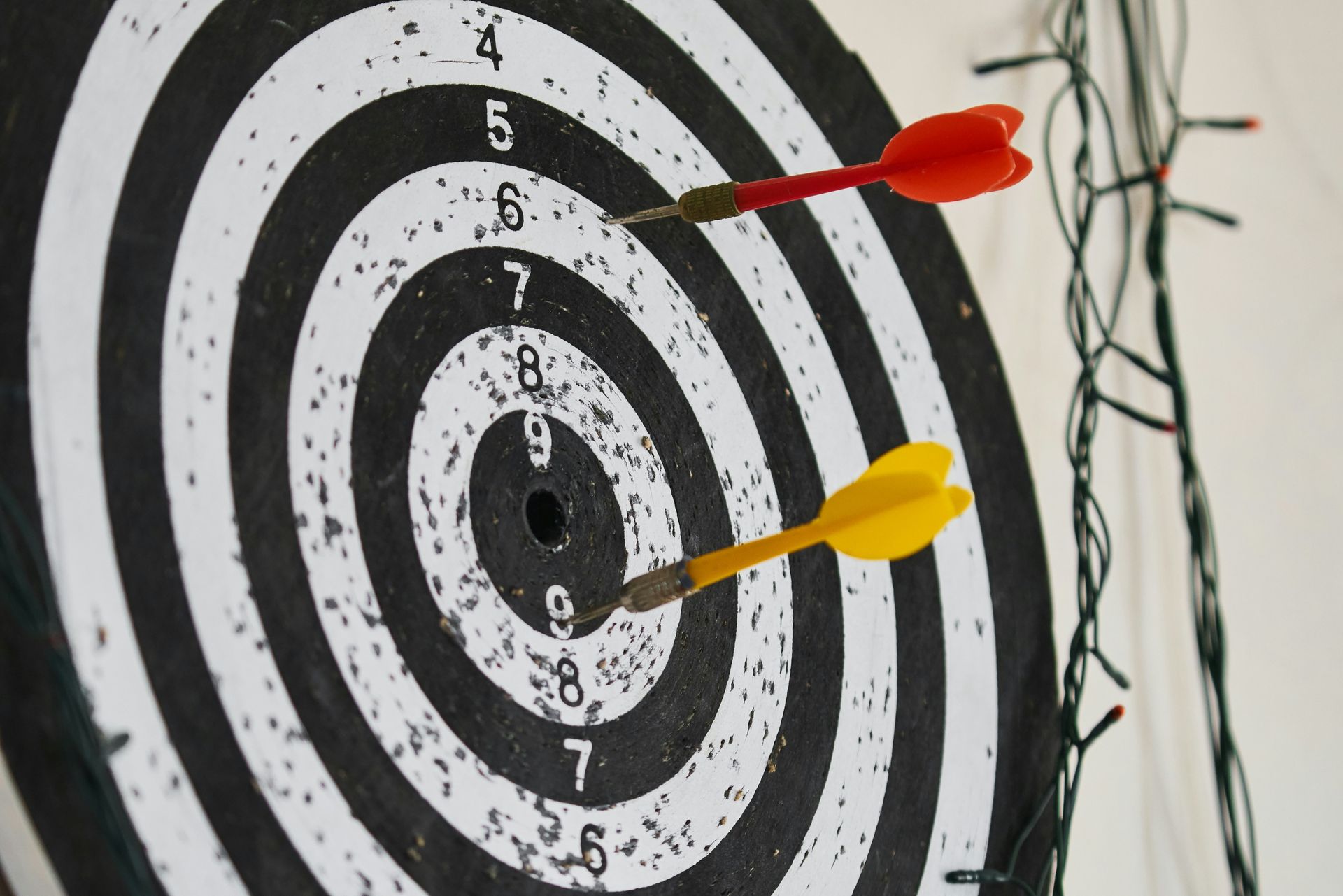 A dartboard with a bullseye hit and wear marks, and a green wire to the side.