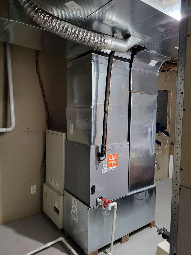 Unité de climatisation dans un sous-sol. Composants métalliques rectangulaires, conduits, tuyaux et boîtes électriques.