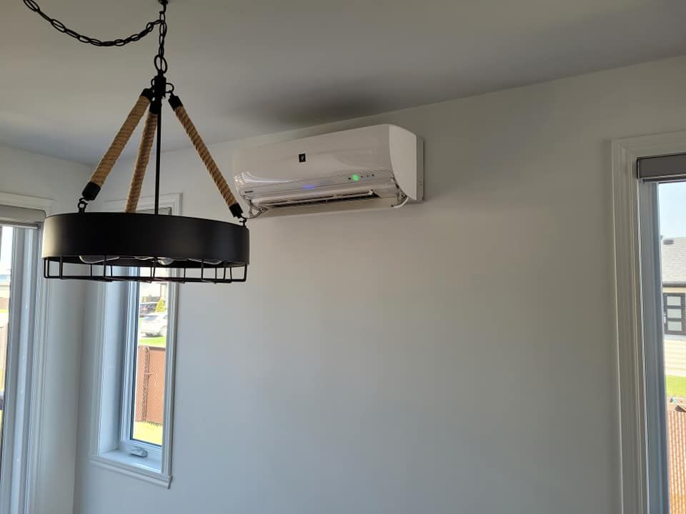 Climatiseur mural au-dessus de la fenêtre. Luminaire noir suspendu au plafond. Murs et fenêtres blancs.