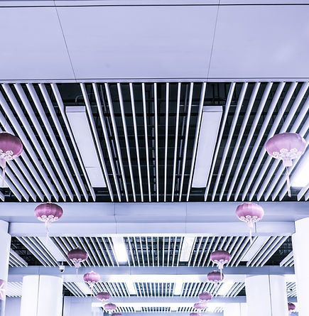 Plafond habillé de luminaires encastrés et de lanternes roses suspendues, dans un cadre architectural moderne.