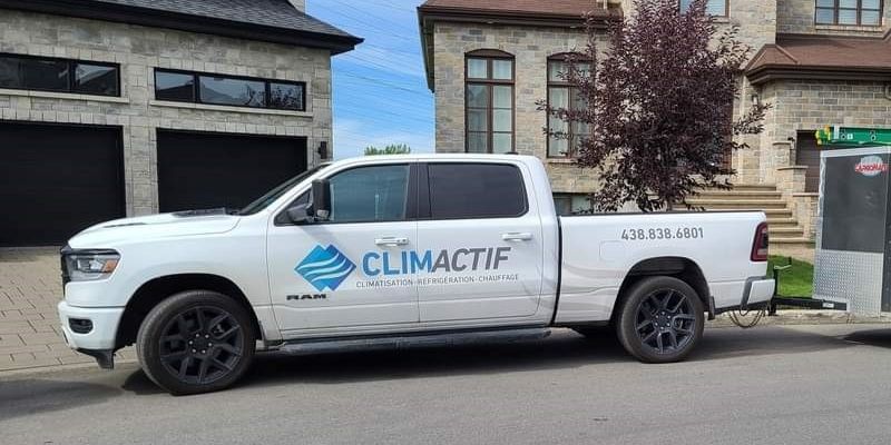 Camion blanc portant le logo « Climactif » stationné dans la rue devant des maisons en pierre.