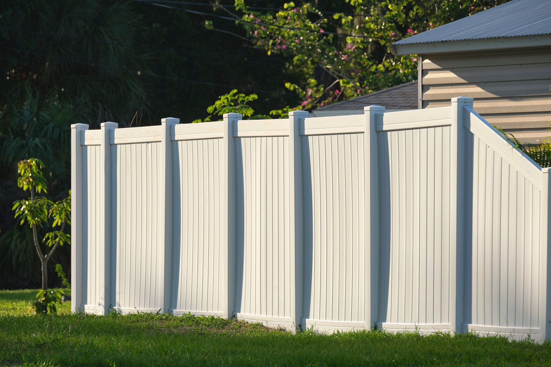 White vinyl fence beside a house in a sunny yard