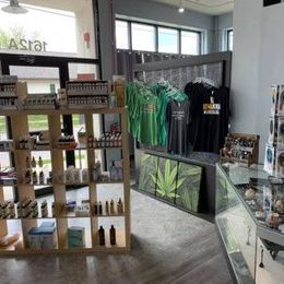 Inside of a shop, shelves with products, clothing on display, and a decorative cannabis leaf.
