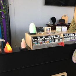 A counter display with essential oils, jewelry, and salt lamps in a shop.